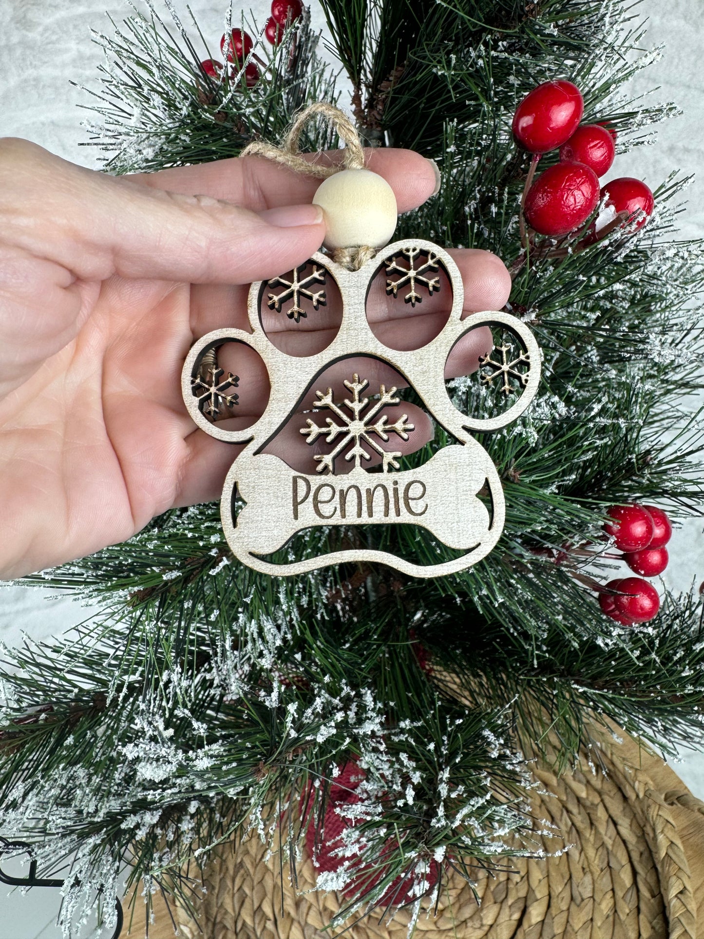 Hand holding personalized dog ornament on tree